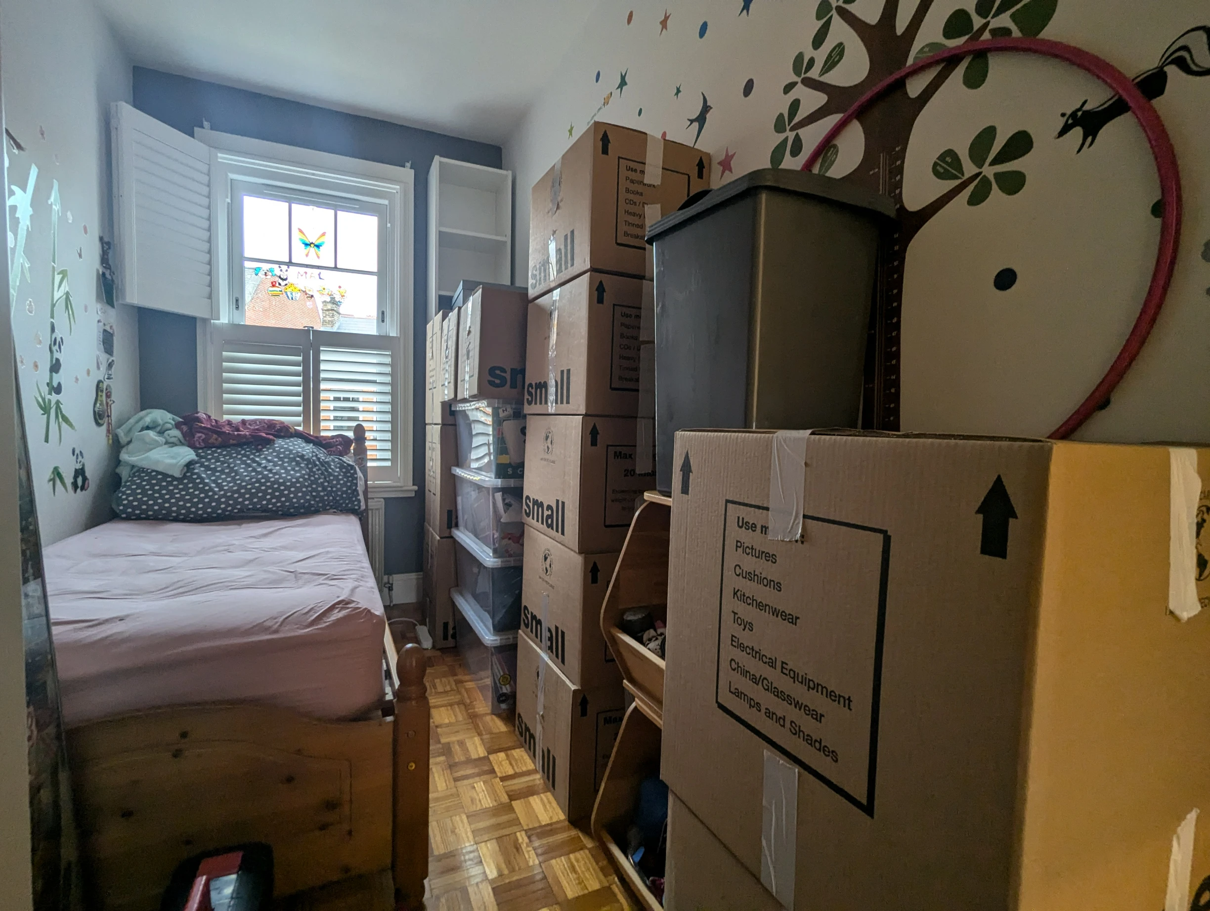 A neatly packed boxes stacked on top of another next to a child bedroom wall
